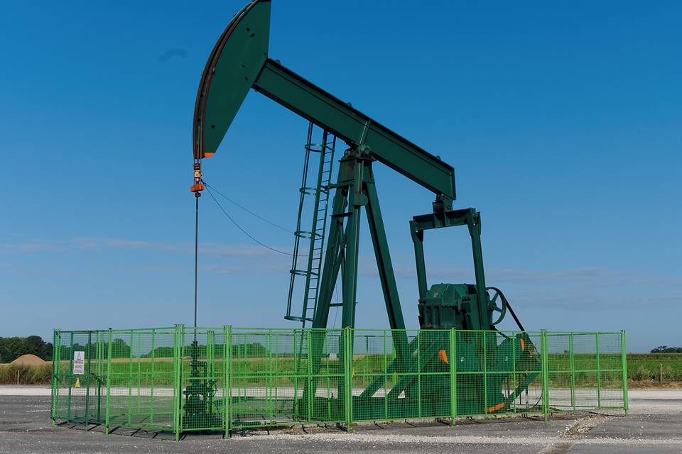 A set of oil developing machine is parking in the oil field fence made of welded wire mesh panels.